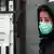 Frau mit Mundschutz vor einer Klinik in Minsk