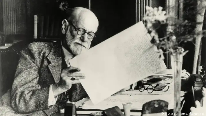 Sigmund Freud mirando una hoja de papel con escritura (picture-alliance / akg-images)