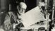 Sigmund Freud mirando una hoja de papel con escritura (picture-alliance / akg-images)