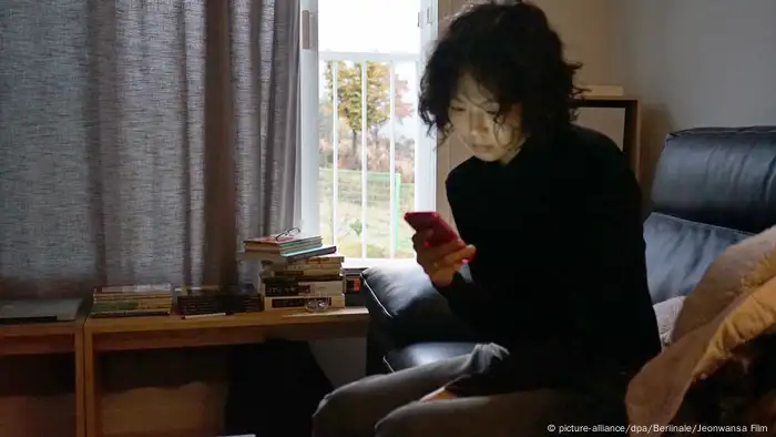 Eine junge Frau sitzt auf einem Sofa und schaut in ihr Smartphone (picture-alliance/dpa/Berlinale/Jeonwansa Film )