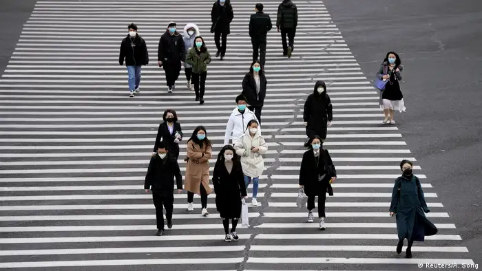 China Shanghai | Menschen mit Gesichtsmasken überqueren Straße