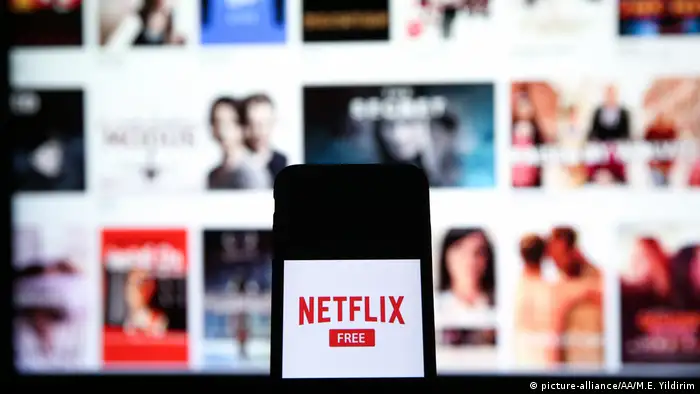 In this photo illustration a mobile phone screen displays the Netflix logo in front of a computer screen showing Netflix series and movies screen in Istanbul