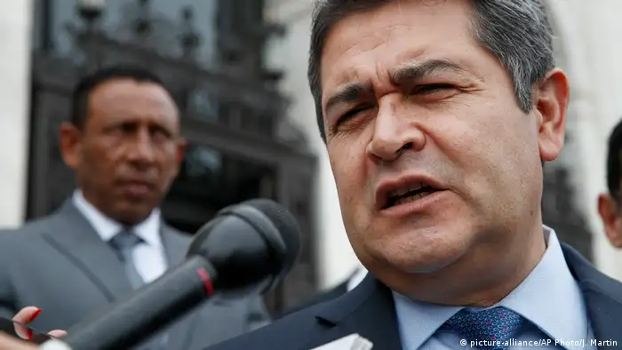 A close-up of Honduras Juan Orlando Hernandez's face. He is speaking into a microphone.