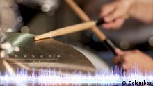 music, people, musical instruments and technology concept - close up of musician with drumsticks playing drum kit at concert at sound recording studio