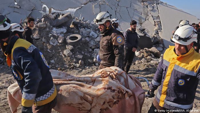 Members of the Syrian Civil Defence, also known as the White Helmets, recover bodies in the town of Maaret Misrin following Syrian government forces airstrikes