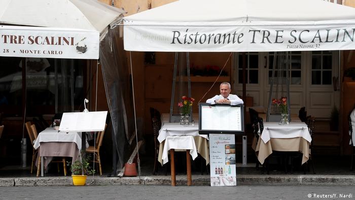 A man stands outside an empty restaurant in Rome