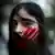 A woman in Lebanon, with a red hand painted on her face, protests against sexual harassment