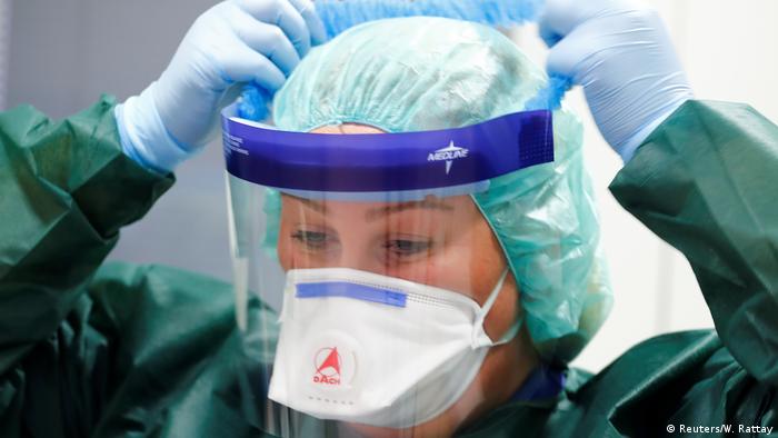 A nurse putting on protective gear