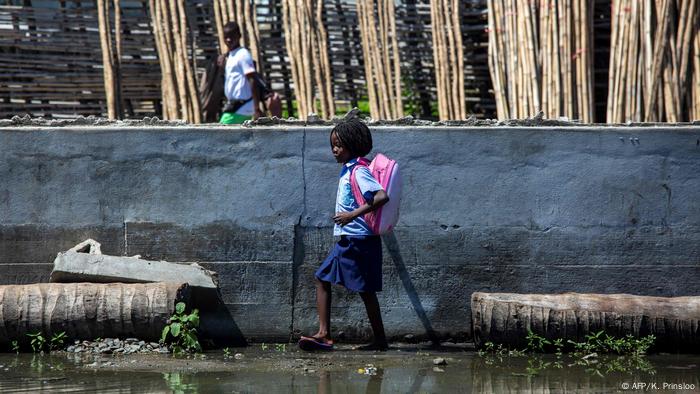 A schoolchild in Beira, Mozambique, walking across a flooded schoolyard