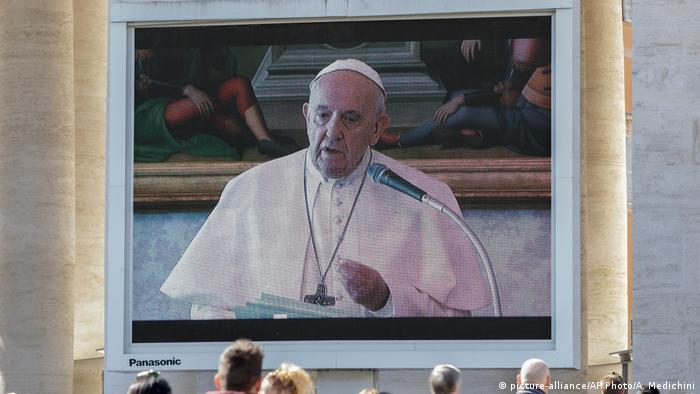 Spectators watch Pope Francis deliver the Angelus prayer on a giant screen, in St. Peter's Square, at the Vatican on Sunday