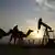 Silhueta de homem montado em camelo com equipamento de poço de petróleo ao fundo