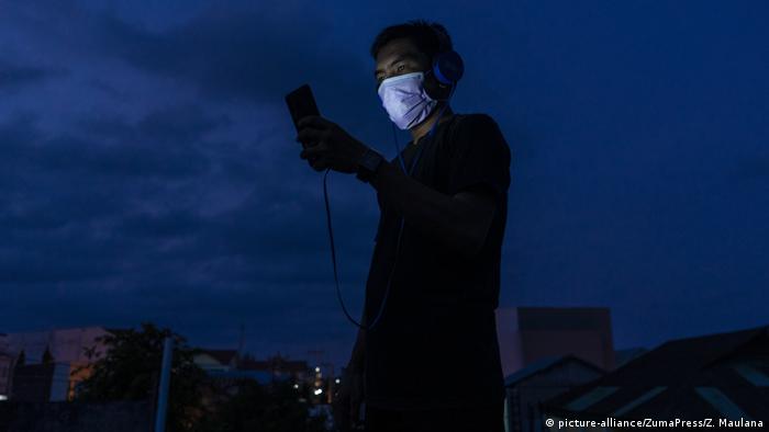 A man wearing a mask holding a cellphone