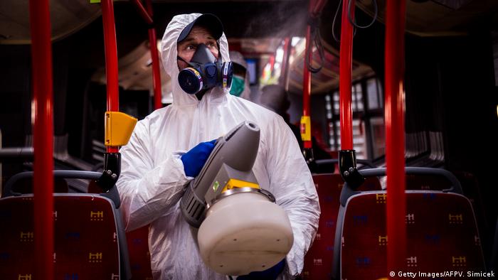 Man in full medical protective gear sprays bus