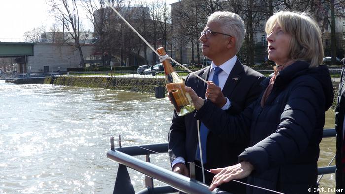 Ashok Sridharan and Nike Wagner holding a bottle of champagne on a rope