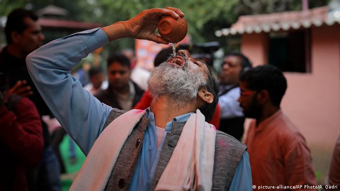 An Indian Hindu woman drinks cow urine during an event organized by a Hindu religious group to promote consumption of cow urine as a cure for the new coronavirus in New Delhi, India