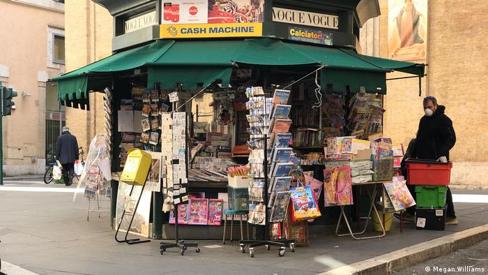 Un hombre atiende un quiosco de revistas en una calle de Roma con mascarilla. (Archivo).