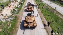 Syrians in protest surround a Turkish military M60T tank as they attempt to block traffic on the M4 highway, which links the northern Syrian provinces of Aleppo and Latakia, before incoming joint Turkish and Russian military patrols (as per an earlier agreed upon ceasefire deal) in the village of al-Nayrab, about 14 kilometres southeast of the city of Idlib and seven kilometres west of Saraqib in northwestern Syria on March 15, 2020. - Russian President Vladimir Putin and his Turkish counterpart Recep Tayyip Erdogan reached a deal on March 5 to create a security corridor with joint Turkish and Russian patrols starting on March 15 along the key M4 highway in northern Syria, which runs roughly parallel to the border with Turkey, from northeastern Kurdish-controlled regions to the Mediterranean coast. (Photo by AAREF WATAD / AFP)