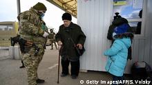 16.03.2020 *** A female Ukrainian border guard wearing a protective face mask helps an elderly woman coming back from Ukraine to the territory controlled by Russia-backed separatists at the checkpoint near Novotroitske village, Donetsk region, on March 16, 2020. - Ukraine said Friday it would close its borders to foreigners for at least two weeks and stop all flights to prevent the spread of the new coronavirus, as it reported its first COVID-19 fatality. Ukraine's borders will be closed to foreign citizens for two weeks, Oleksiy Danilov, secretary of the country's Security and Defence Council, told reporters, adding that the measure will take effect in 48 hours. (Photo by SERGEY VOLSKIY / AFP) (Photo by SERGEY VOLSKIY/AFP via Getty Images)
