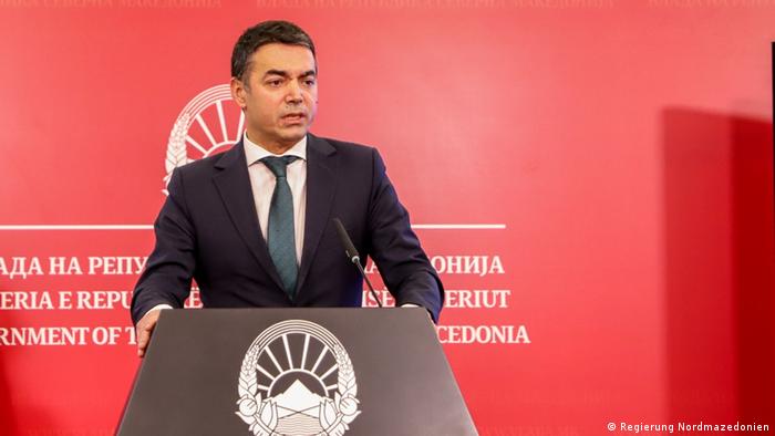 Former Macedonian Foreign Minister Nikola Dimitrov stands at a podium against a red backdrop