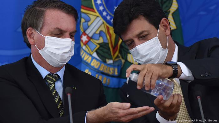 El ahora exministro de Salud de Brasil, Luiz Henrique Mandetta (derecha), aplica gel antibacterial en las manos del presidente Jair Bolsonaro en el Palacio Presidencial de Planalto, en Brasilia (18.03.2020)