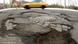 A close up photo of potholes on a German street with a yellow car driving by A close up photo of potholes on a German street with a yellow car driving by