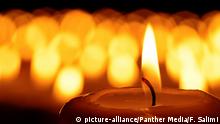 Candle in front of many defocused candleflames creating a spiritual atmosphere and in remembrance of the victims of terror and violence | Verwendung weltweit, Royalty free: Bei werblicher Verwendung Preis auf Anfrage., Keine Weitergabe an Wiederverkäufer.