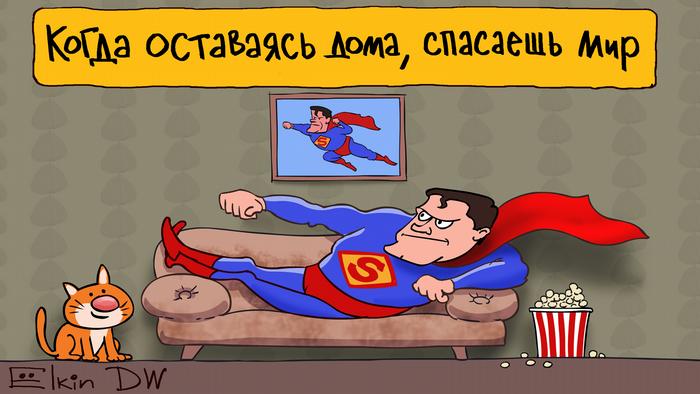 Мужчина в костюме Супермена лежит на диване, а над ним висит плакат Когда оставаясь дома, спасаешь мир