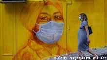 A pregnant woman wearing a face mask as a precautionary measure walks past a street mural in Hong Kong, on March 23, 2020, after the citys Chief Executive announced plans to temporarily ban the sale of alcohol in bars and restaurants as a measure to help stop the spread of the COVID-19 caused by the novel coronavirus. - Hong Kong will ban all non-residents from entering the city from midnight on March 24, 2020 in a bid to halt the coronavirus, its leader says, as she unveils plans to stop restaurants and bars serving alcohol. (Photo by ANTHONY WALLACE / AFP) (Photo by ANTHONY WALLACE/AFP via Getty Images)