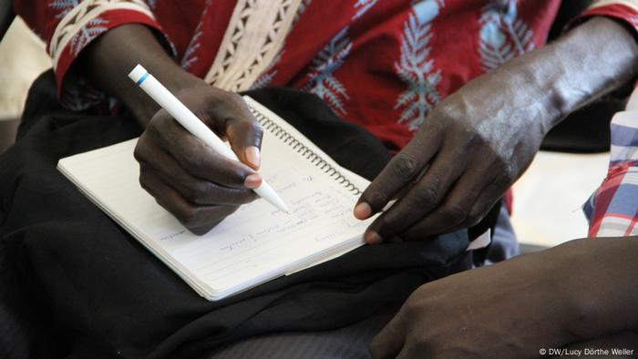 A man writes on a notebook.