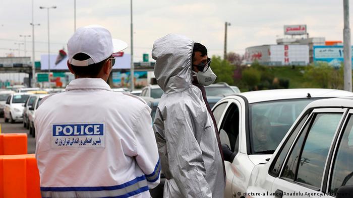 Officials check body temperatures in a line of cars in Tehran