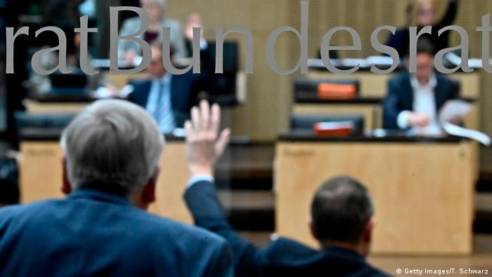 Bundesrat members raise their hands to vote during a session