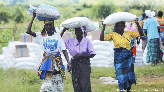 Women carry bags of corn they received as food aid, in Mudzi about 230 Kilometers northeast of the Zimbabwean capital Harare