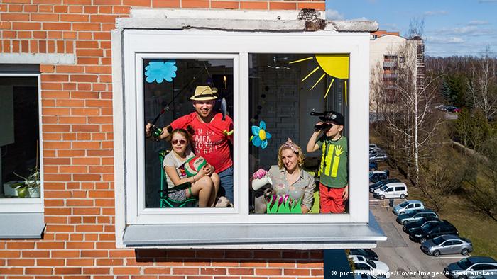 Eine Familie schaut aus einem bunt beklebten Fenster (picture-alliance/Cover Images/A. Vasilauskas)