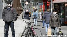 Ein Mann und eine Frau mit Schutzmasken in einer Berliner Einkaufsstrasse, versuchen sich vor dem Coronavirus zu schuetzen. Das oeffentliche Leben in Berlin ist nach den zuletzt beschlossenen Schutzmassnahmen gegen die Ausbreitung des Coronavirus nahezu zum Erliegen gekommen. Betroffen sind alle Sehenswerdigkeiten, Museen, Plaetze, Strassen, Restaurants, Universitaeten, Einkaufszentren. | Verwendung weltweit
