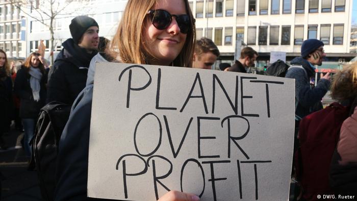 Junge Frau auf einer Demonstration von Fridays for Future in Köln. Auf dem Plakat steht: Planet over Profit