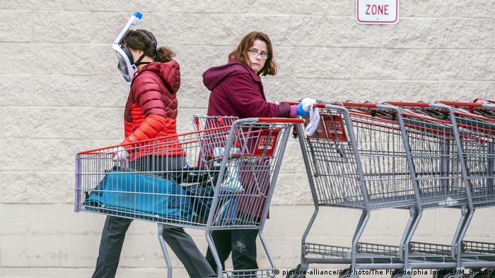 Two women push shopping carts during the coronavirus pandemic, one wears a snorkel mask