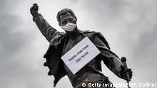 A photograph taken on March 23, 2020 in Montreux shows the statue of Queen's late singer Freddie Mercury wearing a protective facemask and adorned with a placard with a message raising awareness against the spread of the COVID-19 (novel coronavirus), on the shore of the Lake Geneva. - The tribute statue inspired by the cover of Queen's final album Made in Heaven was unveiled on November 1996, five years after Mercury a long-time resident of Montreux passed away. (Photo by Fabrice COFFRINI / AFP) (Photo by FABRICE COFFRINI/AFP via Getty Images)