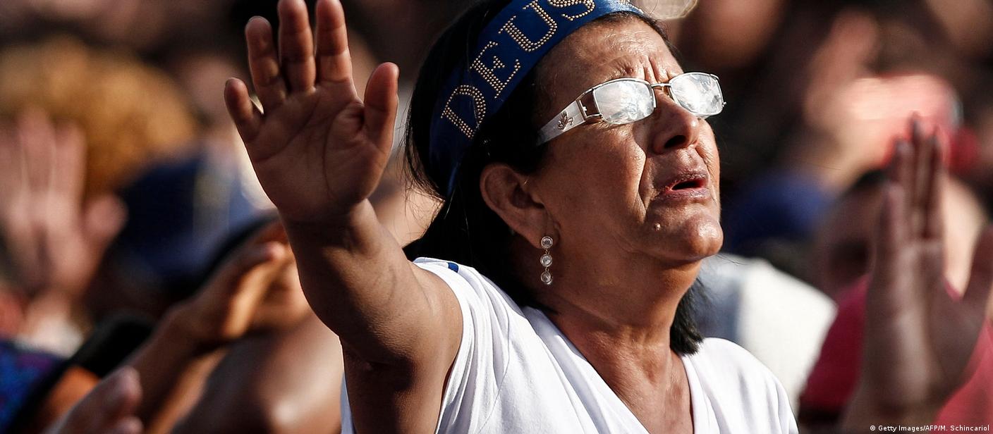 Mulher com faixa escrito "Deus" na cabeça reza durante a Marcha para Jesus, em junho de 2019