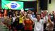 Evangélicos oram de braços levantados em salão que tem a bandeira do Brasil em telão