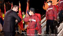 An handout picture taken and released by the Serbia's presidential press office on March 21, 2020, shows Serbian President Aleksandar Vucic (L) welcoming a group of Chinese doctors at Belgrade's airport. - When six Chinese doctors landed in Belgrade two weeks ago, Serbia's president greeted them with elbow-bumps before laying a kiss on their country's flag, a gesture of gratitude that sent Chinese social media aflutter. These doctors are now running the Balkan state's COVID-19 strategy, as Serbia becomes a willing theatre for Beijing's mask diplomacy. For weeks China has been showering European countries with millions of face masks, test kits and other aid, recasting itself as the hero in the battle against coronavirus. (Photo by Dimitrije GOLL / Serbia's Presidential press service / AFP) / RESTRICTED TO EDITORIAL USE - MANDATORY CREDIT AFP PHOTO / Dimitrije GOLL/ Serbia's Presidential press service - NO MARKETING - NO ADVERTISING CAMPAIGNS - DISTRIBUTED AS A SERVICE TO CLIENTS