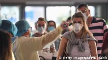 A health worker checks the body temperature of passengers bound for Frankfurt at Dubai International Airport on April 6, 2020, as Emirates Airline resumed a limited number of outbound passenger flights after its COVID-19 coronavirus-enforced stoppage. (Photo by KARIM SAHIB / AFP) (Photo by KARIM SAHIB/AFP via Getty Images)