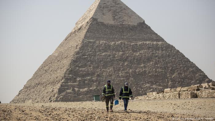 Workers with protective gear in front of the Great Pyramids in Giza, Egypt - Lonely Places (picture-alliance/dpa/G. Hamdy)