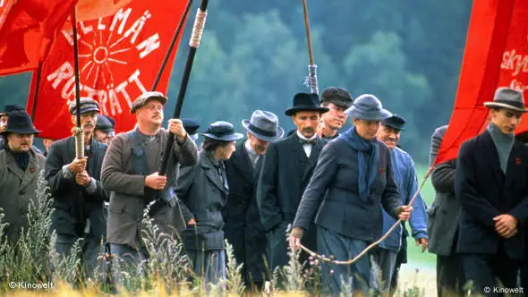 Szene aus dem Film "Die besten Absichten" von Bille August: Eine Gruppe von menschen mit roten Fahnen auf Feld (Arthaus)