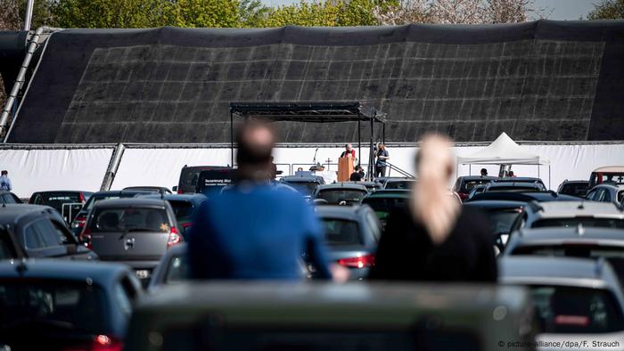 Ostergottesdienst im Autokino: Paarschaut aus dem Autodach auf Bühne und Pfarrer