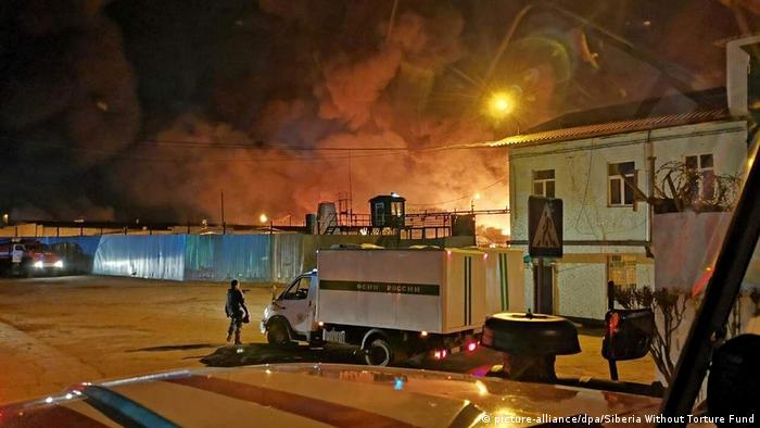 Riot at Angarsk's Correctional Facility No 15, buildings, truck, fire in the background