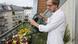 A man waters plants with a watering can on his balcony A man waters plants with a watering can on his balcony