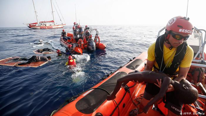 Helfer auf zwei Schlauchbooten retten Migranten aus dem Wasser