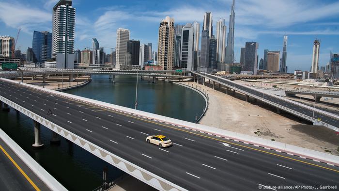 A lone taxi cab drives over a typically gridlocked highway with the Burj Khalifa, the world's tallest building, in the skyline behind it in Dubai.