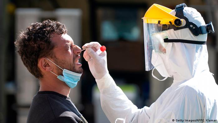 Врач берет мазок из носа у мужичны во время тестирования на коронавирус в Словакии