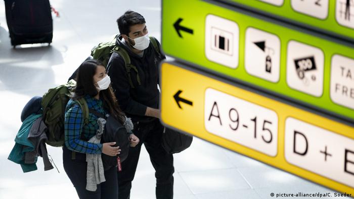 Two travelers at the Berlin Tegel Airport wearing coronavirus prevention face masks
